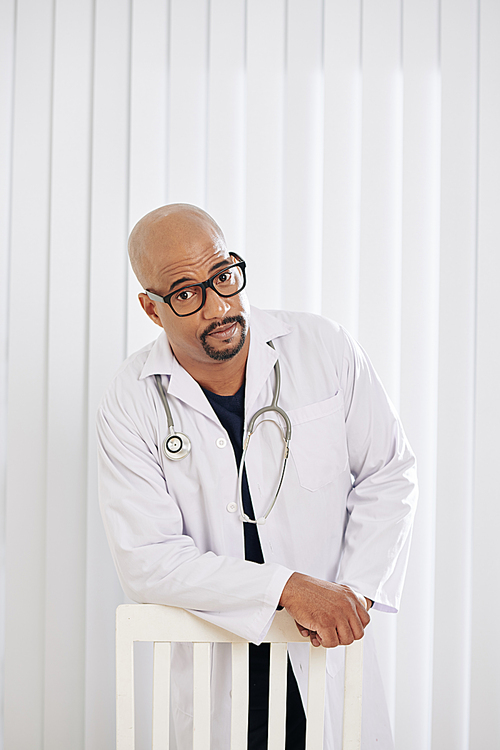 Portrait of handsome mixed-race doctor in glasses and white labcoat