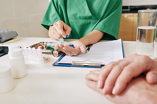 Close-up image of nurse counting weekly ammount of pills for senior patient
