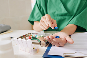 Hands of nurse putting prescribed pills for patient in metal plate