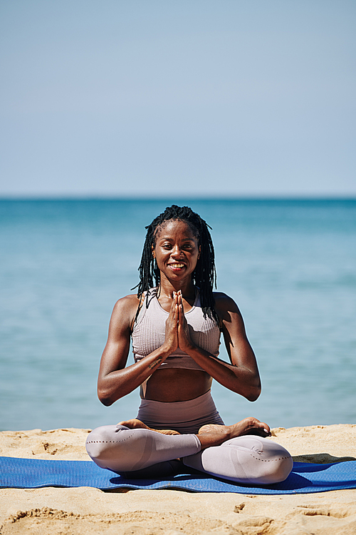 Smiling young slim woman in lotus position strain outdoors with hands in master gesture and