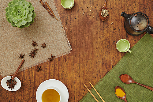 High angle view of wooden table with cup of green tea and aromatic spices