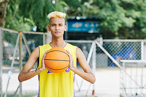 Portrait of young serious basketball player standing street court ready to throw a ball