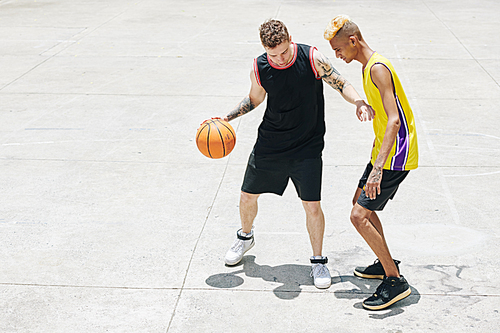 Two basketball athlets in uniform training on outdoor court on summer day