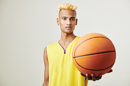 Handsome young basketball player with fashionable hairstyle offering you ball