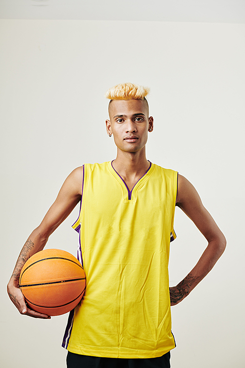 Studio portrait of young fit basketball player posing with wall against white background