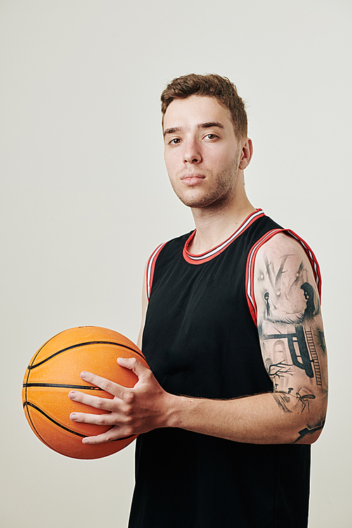 Portrait of serious confident professional basketball player with ball in hand 
