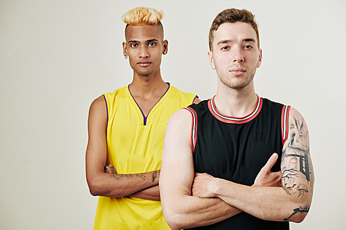 Studio portrait of confident multi-ethnic basketball team players standing one behind another and 