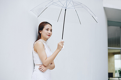 Positive young attractive Asian woman with transparent umbrella