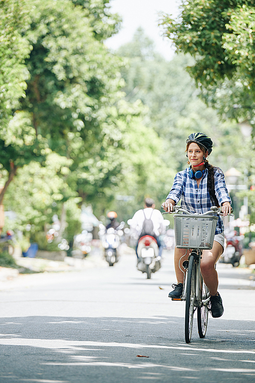 Cheerful pretty young woman enjoying bicycle ride on summer day