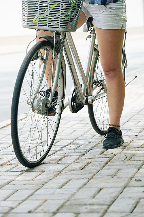 Cropped image of woman sitting on bicycle and resting after long ride in park