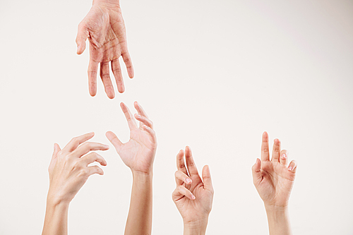 Close-up of young people stretching hands and supporting each other isolated on white