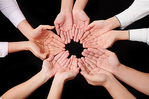 Close-up of people making circle from their hands over black background