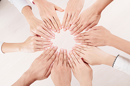 Close-up of group of people putting their hands in circle and showing their manicures over white background