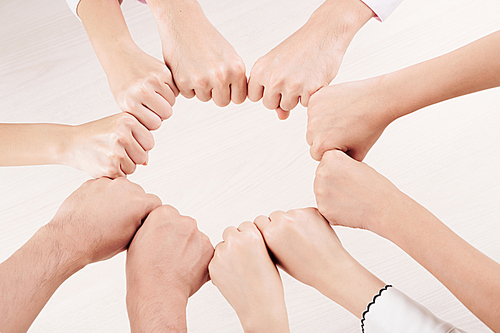 Close-up of group of people hiding their fingers and making circle from fists over white background
