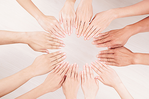 Close-up of multiethnic group of people putting their hands on the table in the form of circle