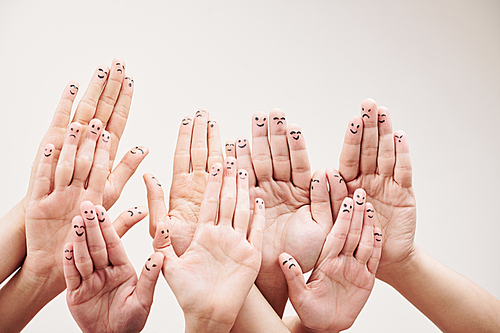 Close-up of group of people showing smileys on their fingers of hands against the white background
