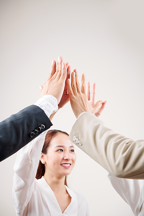 Asian young businesswoman standing and giving a high five to her colleagues and smiling
