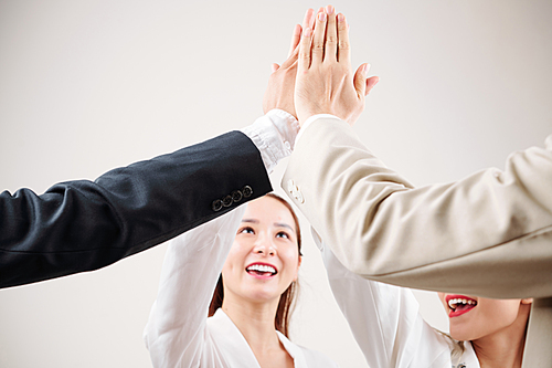Group of business people standing and giving a high five to each other after successful meeting
