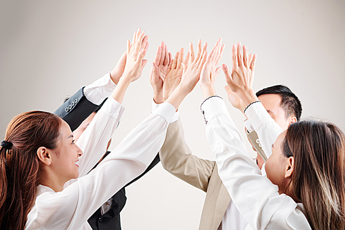 Group of Asian business people raising their arms up giving a high five to each other and celebrating their success