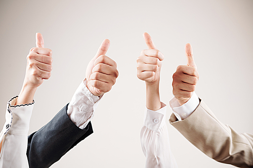 Close-up of group of business people showing thumbs up and satisfied of their work isolated on white