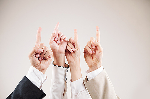 Close-up of business team raising their hands together and pointing up against the white background