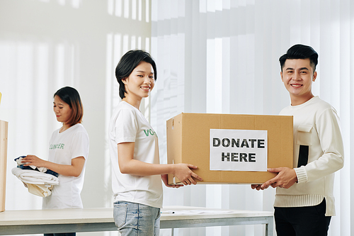 Positive Vietnamese volunteers carrying box with donated clothes