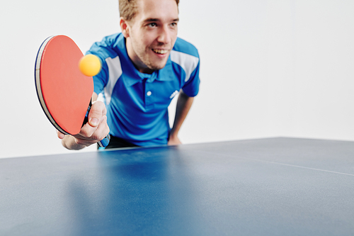 Smiling ping pong player striking ball with the racket, selective focus