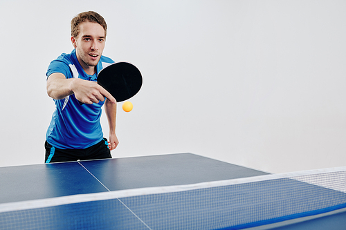 Young sportsman playing ping pong at competition and hitting the ball back