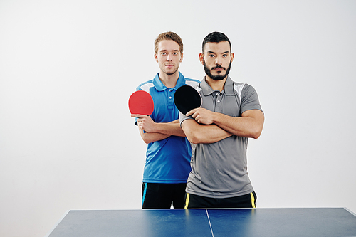 Portrait of multi-ethnic team of table tennis players in uniform posing with rackets