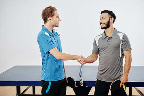 Professional table tennis players shaking hands before playing game at competition