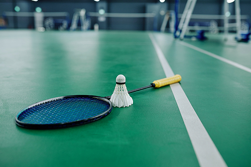 Shuttlecock and racquet on gymnasium floor, selective focus