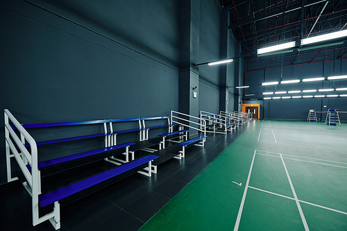 Empty benches for fans and sportsmen in gymnasium with tennis courts