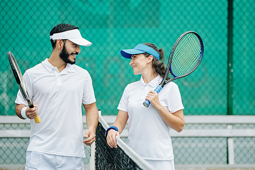 Happy young couple in white uniform enjoying playing tennis together