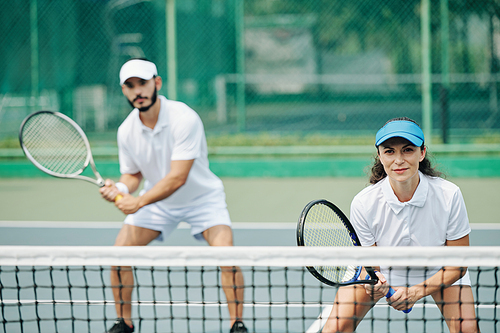 Young couple playing tennis in team and getting ready to hit the ball