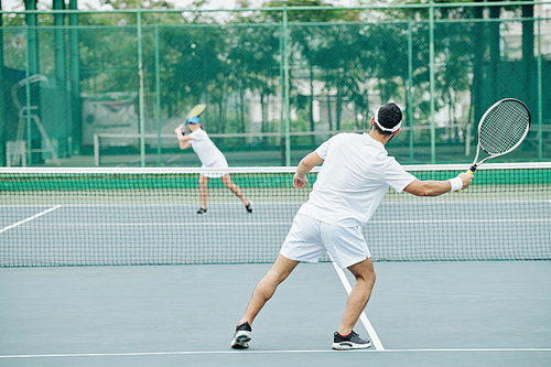 Couple in white uniform having tennis match on court