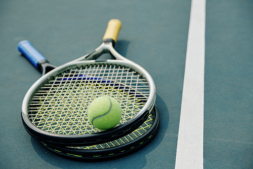 Two tennis rackets and ball on outdoor court, selective focus