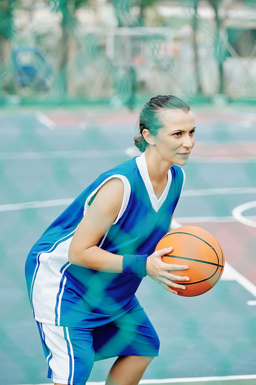 Female basketball player concentrated on game and enjoying playing outdoors