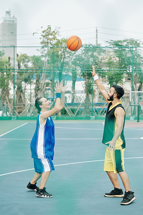 Couple in sports clothes enjoying playing basketball together on outdoor court
