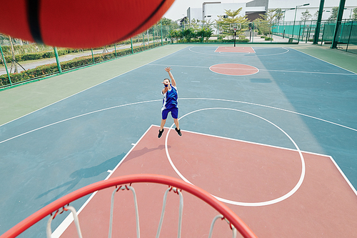 Female professional basketball player throwing ball in basket when playing on outdoor court