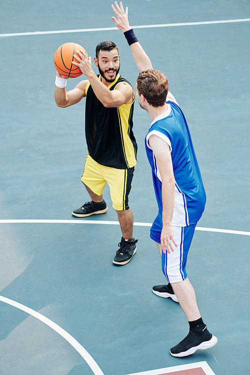 Smiling Hispanic sportsman enjoying playing basketball with friend