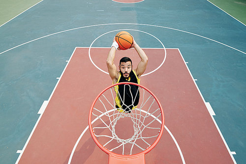Professional Hispanic basketball player jumping and throwing ball in basket