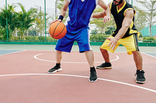 Cropped image of young men playing basketball on outdoor court