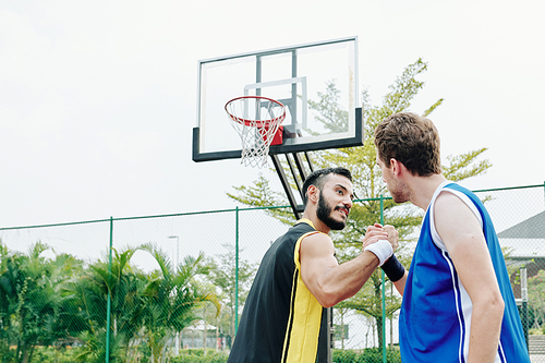 Basketball players shaking hands after playing game together on outdoors court