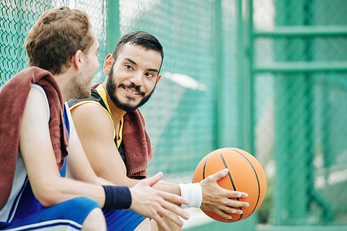 Positive basketball player listening to his friend talking about game or telling news