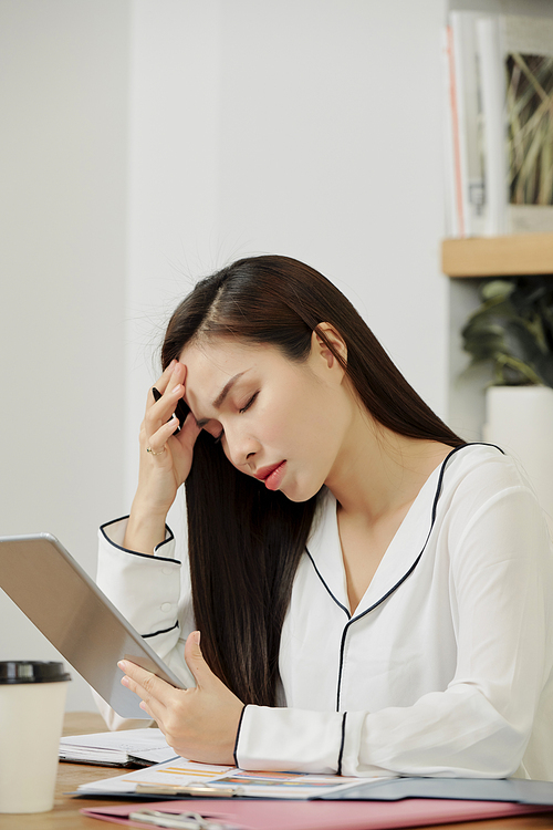 Stressed young female manager having headache after working on project all day long