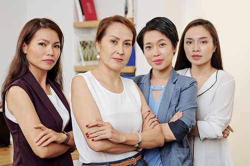 Portrait of confident serious businesswomen folding arms and posing for group photo