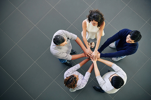Group of multi-ethnic business executive stacking hands to support each other before starting new project, view from above