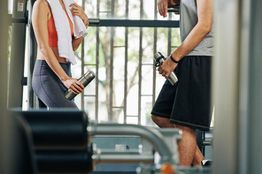 Cropped image of fit couple with themoses and towels discussing new diets and exercises when talking after training