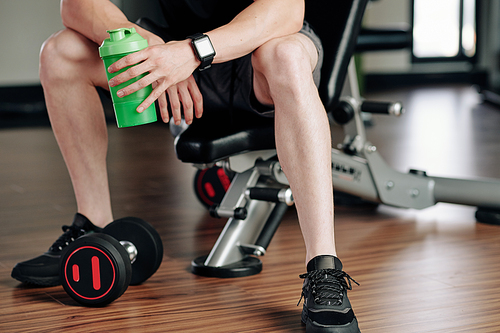 Cropped image of fit young man resting and drinking fresh water after working out with dumbbells