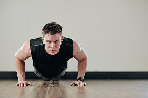 Determined strong young man doing push-ups and 